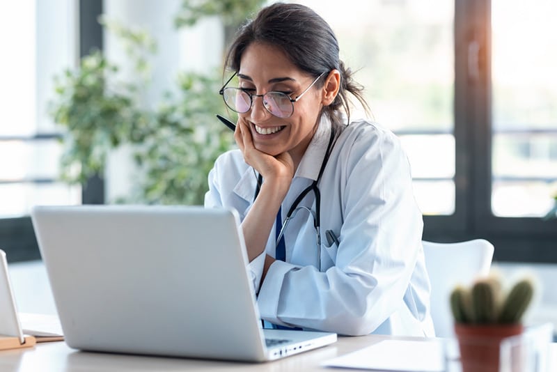 A smiling female doctor looking at a laptop