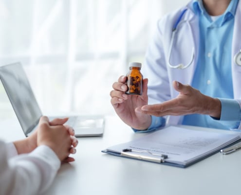 A doctor showing a medicine bottle to a patient