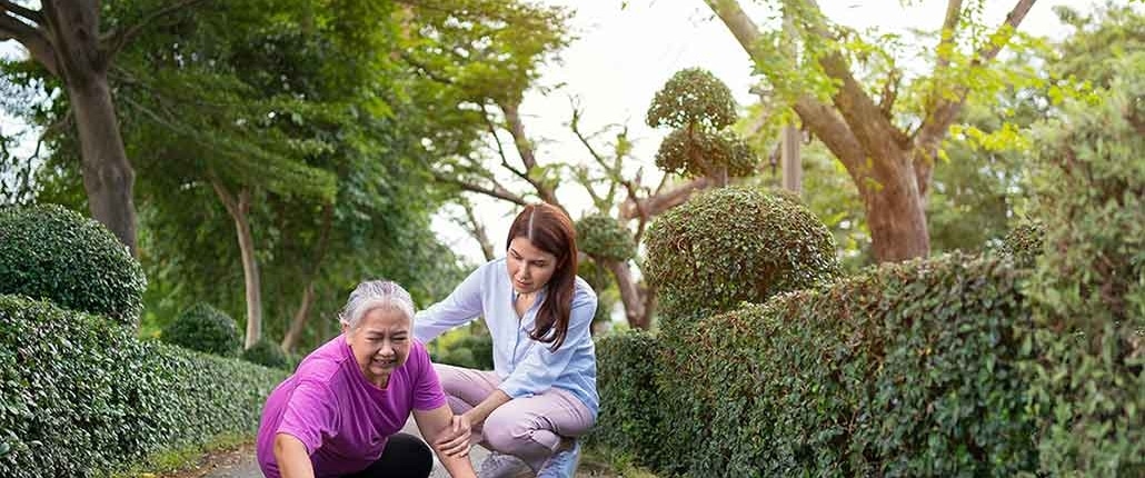 A young woman helping an older woman who has fallen