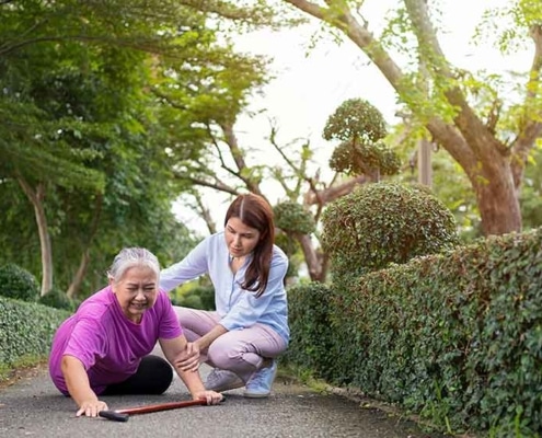A young woman helping an older woman who has fallen