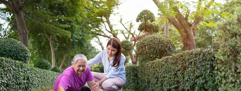 A young woman helping an older woman who has fallen