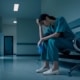 A burned-out nurse sits in a waiting room chair with her head in her hands