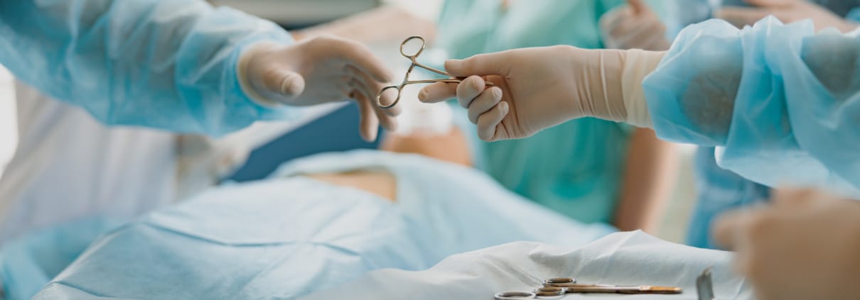 Assistant hands out instruments surgeon during surgery in the operating room