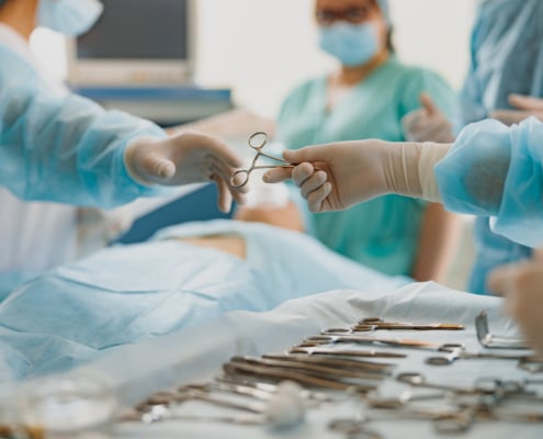 Assistant hands out instruments surgeon during surgery in the operating room