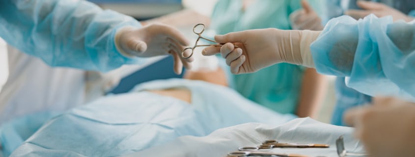 Assistant hands out instruments surgeon during surgery in the operating room