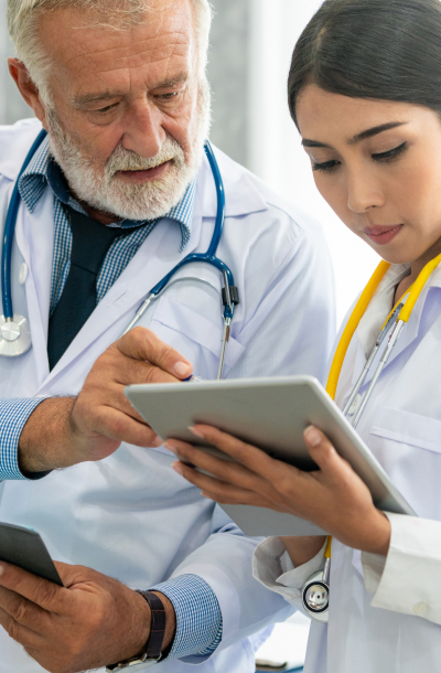 Senior male doctor using tablet computer while discussing with another doctor at the hospital. Medical healthcare staff and doctor service.